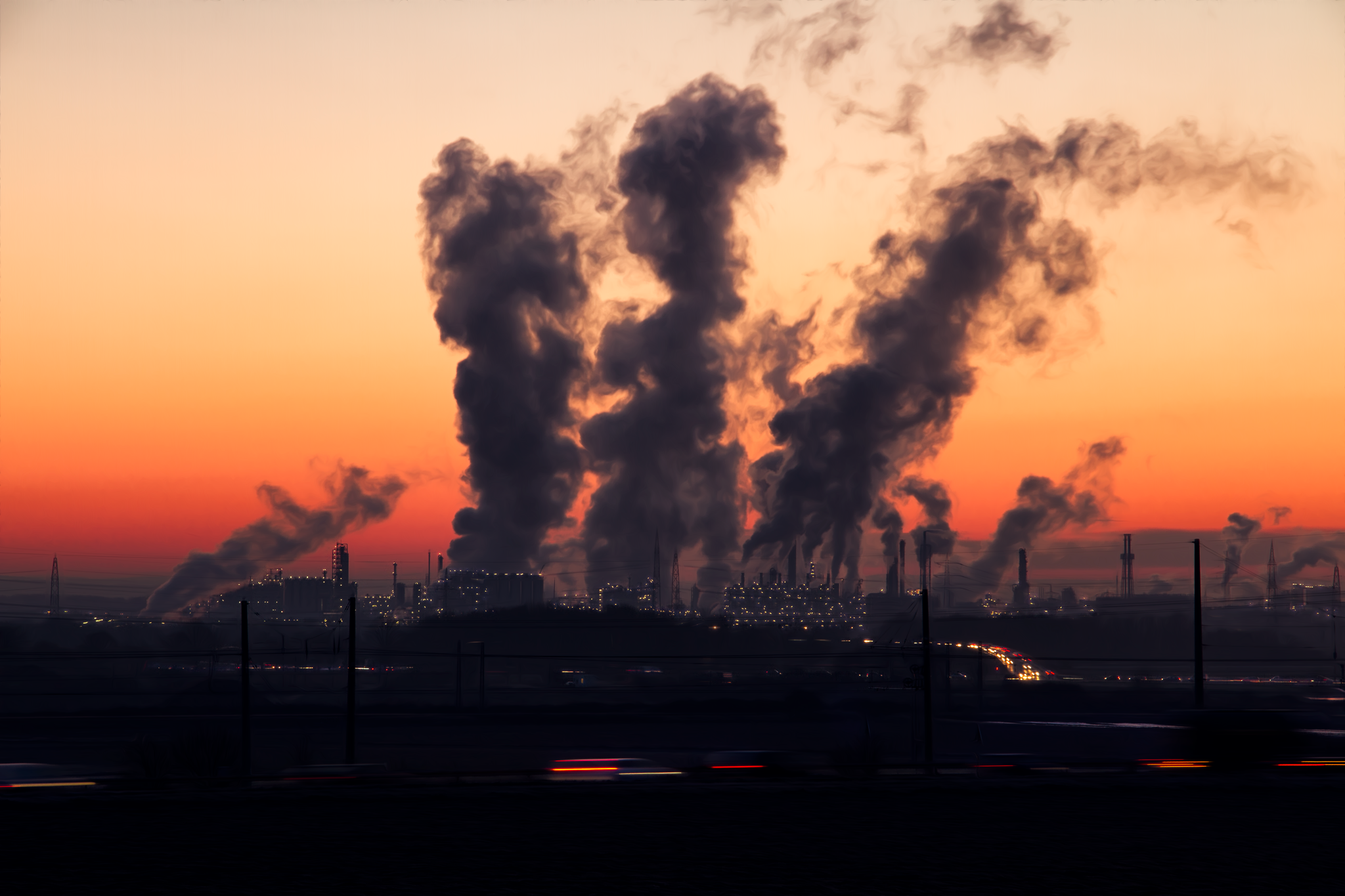 Industrijsko postrojenje i dimnjaci koji ispuštaju onečišćenje zraka u sumrak