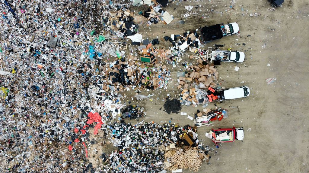 Aerial view of a landfill with scattered waste and vehicles.